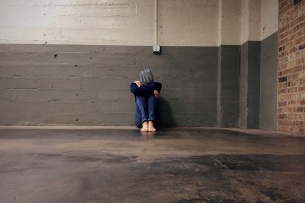 A person all alone in a big building with face hiding.