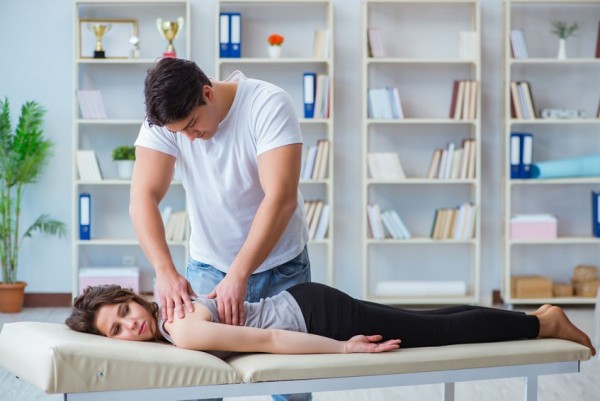 An image of a man placing his hands on a woman laying down treating her with fascial counterstrain.