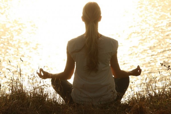 An image of a girl sitting cross-legged doing mindful meditations for pain relief.