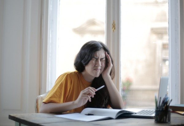 An image of a woman holding her head in pain to represent a migraine to discuss holistic pain management. 