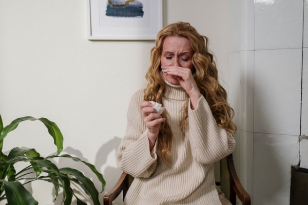 An image of a woman with a running nose and other allergy symptoms to discuss tips on managing allergies naturally.