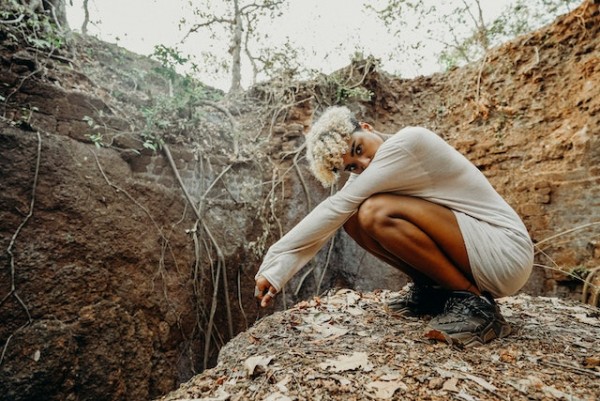 A person sitting by a big hole with roots coming out of the hole to talk about how you have to attack the problem (trauma) at the root.