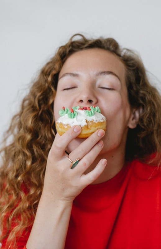 An image of a girl eating a donut to discuss the health risks of poor nutrition.