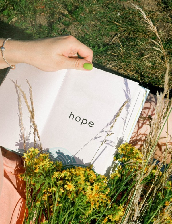 An image of hands holding a journal with the word "hope" in the middle to talk about my health journey and how hope has been so relevant.